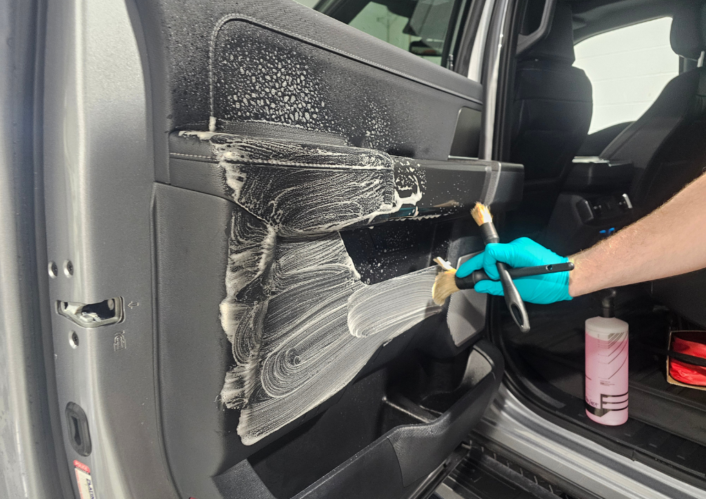 Detailer cleaning interior vehicle door